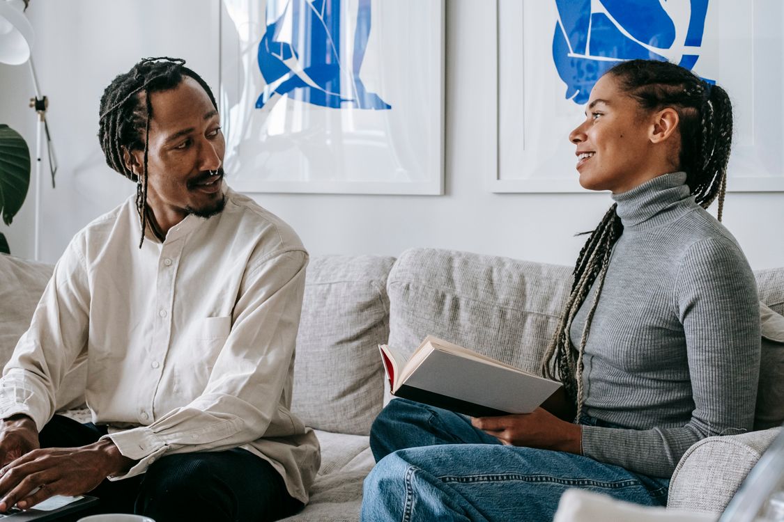 Una pareja conversando en un sofá en una sala luminosa